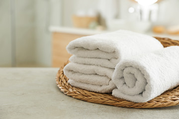 Fototapeta na wymiar Wicker tray with clean towels on table in bathroom