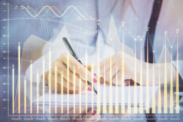 Double exposure of hands making notes with forex chart huds. Stock market concept.