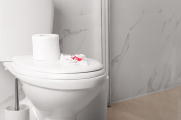 Sheet of paper with blood on toilet bowl in bathroom