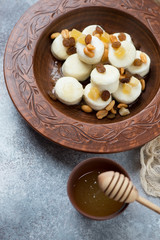 Steamed cottage cheese dumplings with honey served in a clay plate, vertical shot, closeup