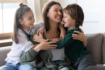 Happy little children hug young mom showing love