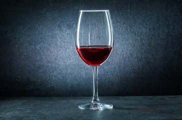 one wineglass with red wine on black background