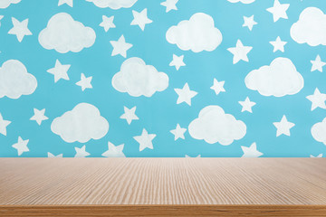 Wooden table near wall with painted clouds and stars. Idea for baby room design