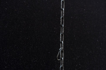 Fototapeta na wymiar Steel chain stretched from top to bottom on a black background