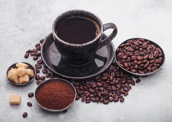 Cup of fresh raw organic coffee with beans and ground powder with cane sugar cubes with coffee tree leaf on light background. Top view