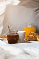 Breakfast in bed, a tray of coffee, croissants, jam, flowers. Honeymoon. Early morning at the hotel. View from above.
