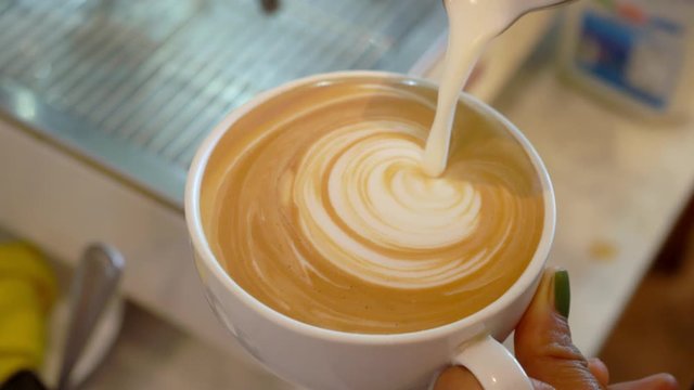 barista pouring milk to make coffee latte art. cafe business shop.A latte is a coffee drink made with espresso and steamed. b-roll footage video 4k.