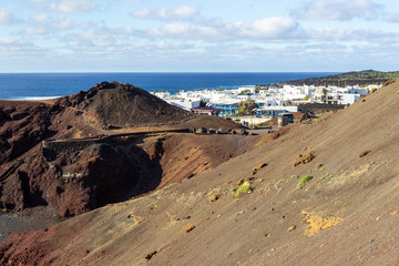 Panoramic view on the coastline of El Golfo with red and black colored volcanic rock formations and lava fields on canary island Lanzarote