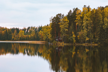 Lake and autumn forest water mirror reflection house in woods landscape in Finland travel scenic view scandinavian nature