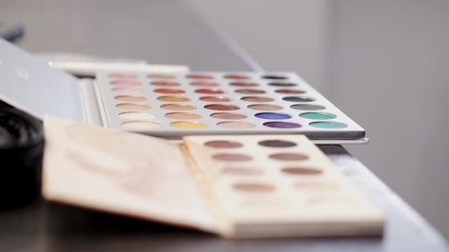 The palette is on a table. It is a salon. There are many colors of shadows.