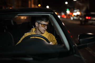 Man driving car in special yellow eyeglasses at night for good night vision