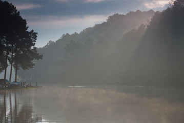 Beautiful light beam over a foggy lake in a morning