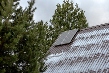 Two solar panels on the snow-covered roof of the house.