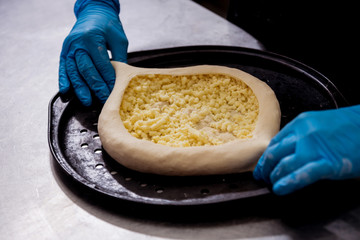 Chef cooking khachapuri with cheese and egg. Georgian national cuisine. Restaurant.