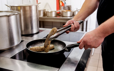 Cooking sausages in a pan. Grilled sausage in a skillet. Restaurant.
