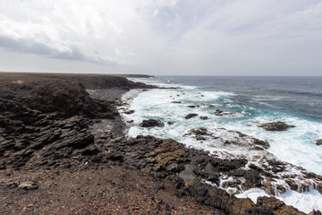 Scenic view at the coastline in the natural park of Jandia (Parque Natural De Jandina) on canary island Fuerteventura with gravel, lava rocks and rough sea with waves