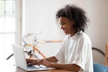 Fototapeta premium Smiling confident African American businesswoman using laptop in office