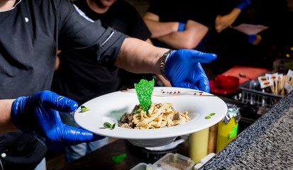 Chef cooking pasta with meat in pan. Italian style cuisine. Restaurant.