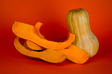 Ripe elongated pumpkin, a very healthy product, shot on a bright orange background.