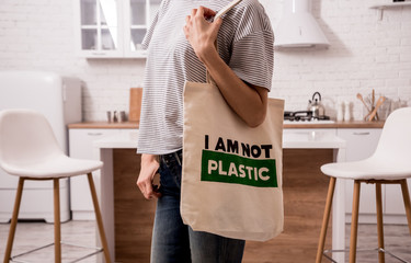 Young girl holding a cloth bag. At the kitchen. I am not plastic. Campaign to reduce the use of...