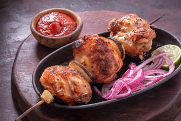 Grilled chicken thighs on a skewer on serving pan