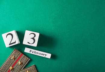 Wooden calendar with the date February 23, epaulettes with golden stars on a green background, top view, place for an inscription