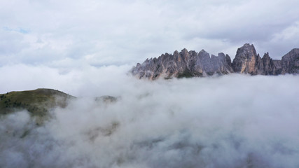 Aerial view of Dolomites Alpine mountains in fog and low clouds. South Tyrol, Italy.