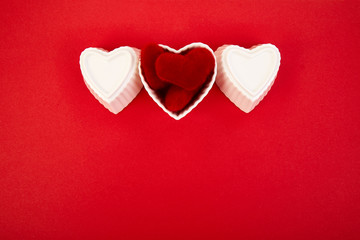 White ceramic hearts with red plush  hearts on red background. Flat lay composition. Romantic, St Valentines Day concept. Love. Copy space.