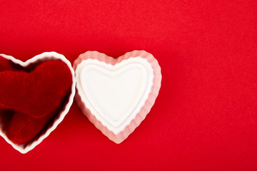 White ceramic hearts with red plush  hearts on red background. Flat lay composition. Romantic, St Valentines Day concept. Love. Copy space.
