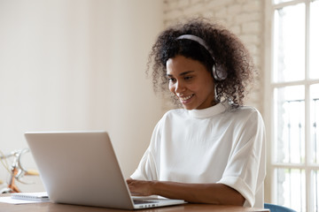 Smiling African American woman wearing headset using laptop in office