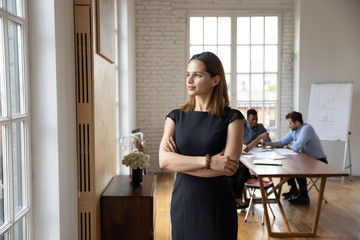 Confident businesswoman standing in office, looking through window