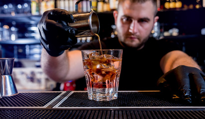Bartender is making cocktail at bar counter. Fresh cocktails. Barman at work. Restaurant. Nightlife.