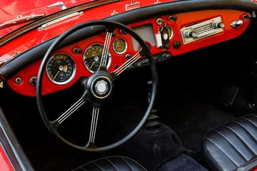 Deurstickers Elegant retro car, vintage cabriolet and red dashboard close-up, behind the big black wheel of such a classy automobile you want to press the gas and go on a sunny summer day in South of France © Konstantin Koreshkov