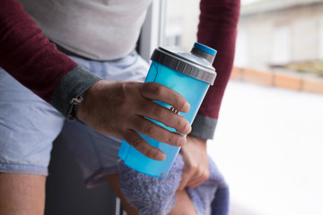 man resting in the gym with water bottle
