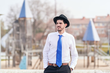 elegant young businessman in a hat and tie looking relaxed with an unfocused background