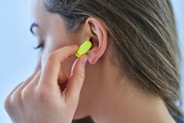 Young brunette woman using earplugs for noise protection at home