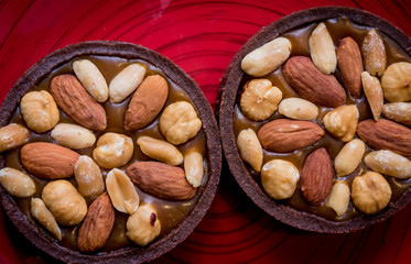 Chocolate cookies with almond nuts on a red plate. Restaurant.