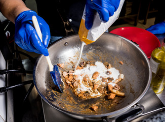 Chef cooking pasta with mussels in pan. Italian style cuisine. Restaurant.