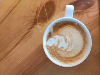 Coffee with froth art on a wooden desk