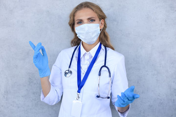 Portrait of female doctor with stethoscope in mask isolated over grey background.