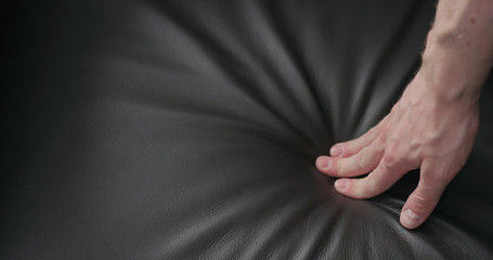 man hand checking dark brown leather cushion closeup