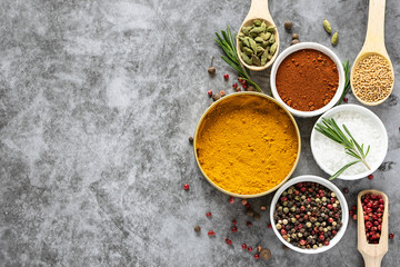 Assortment of spices and herbs on grey concrete background with copy space for your design.