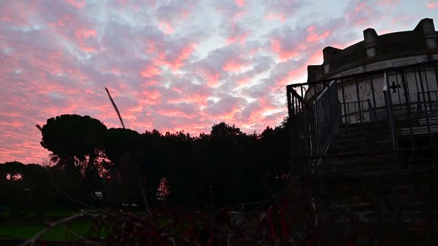 Ravenna, Italy, December 2019. Sunset on the mausoleum of Theodoric is the most famous funerary construction of the Ostrogoths. Particular pink coloring of the clouds at sunset. Dark silhouette.