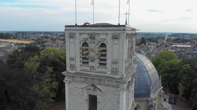 Ancient clocks on cathedrals with flags on in belgium flying around drone