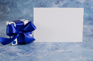 Greeting card for Father's Day or Birthday. Gift box with blank white paper on blue background.