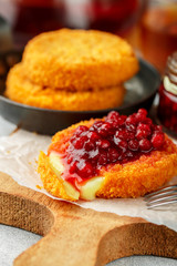 Baked or fried (grilled Camembert or brie cheese with cranberry (lingonberry, cowberry) sauce or jam. Gourmet traditional Breakfast. French cuisine. Selective focus
