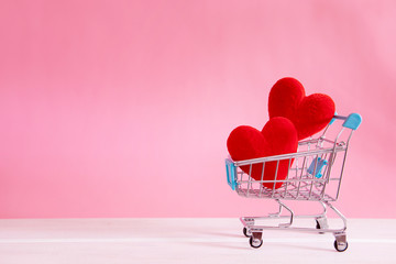 The red Heart shapes in shopping cart on sweet pink background , the love concept for shopping on valentines day with sweet and romantic moment