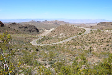 Curved narrow road and a dry rocky hill in Oatman, Arizona - Historic Route 66 - mountains on the horizon. Stock photo