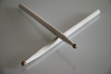 2 white drumsticks laying on a table. Music, instrument
