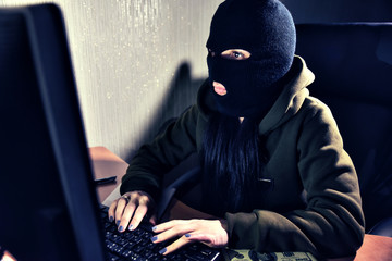 Haker thief in balaclava with computer. 